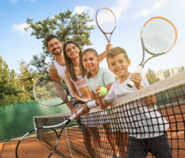 Happy family with tennis rackets on court outdoors